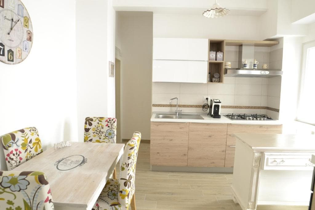 Cucina attrezzata con tavolo da pranzo e sedie floreali nella casa vacanze Dimora Acquamarina a Monopoli centro storico
